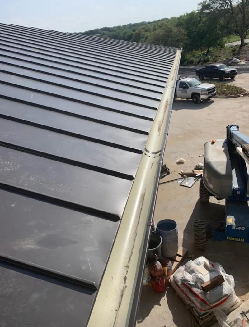 Standing seam panel and gutter detail on a metal roofing jobsite in Logan